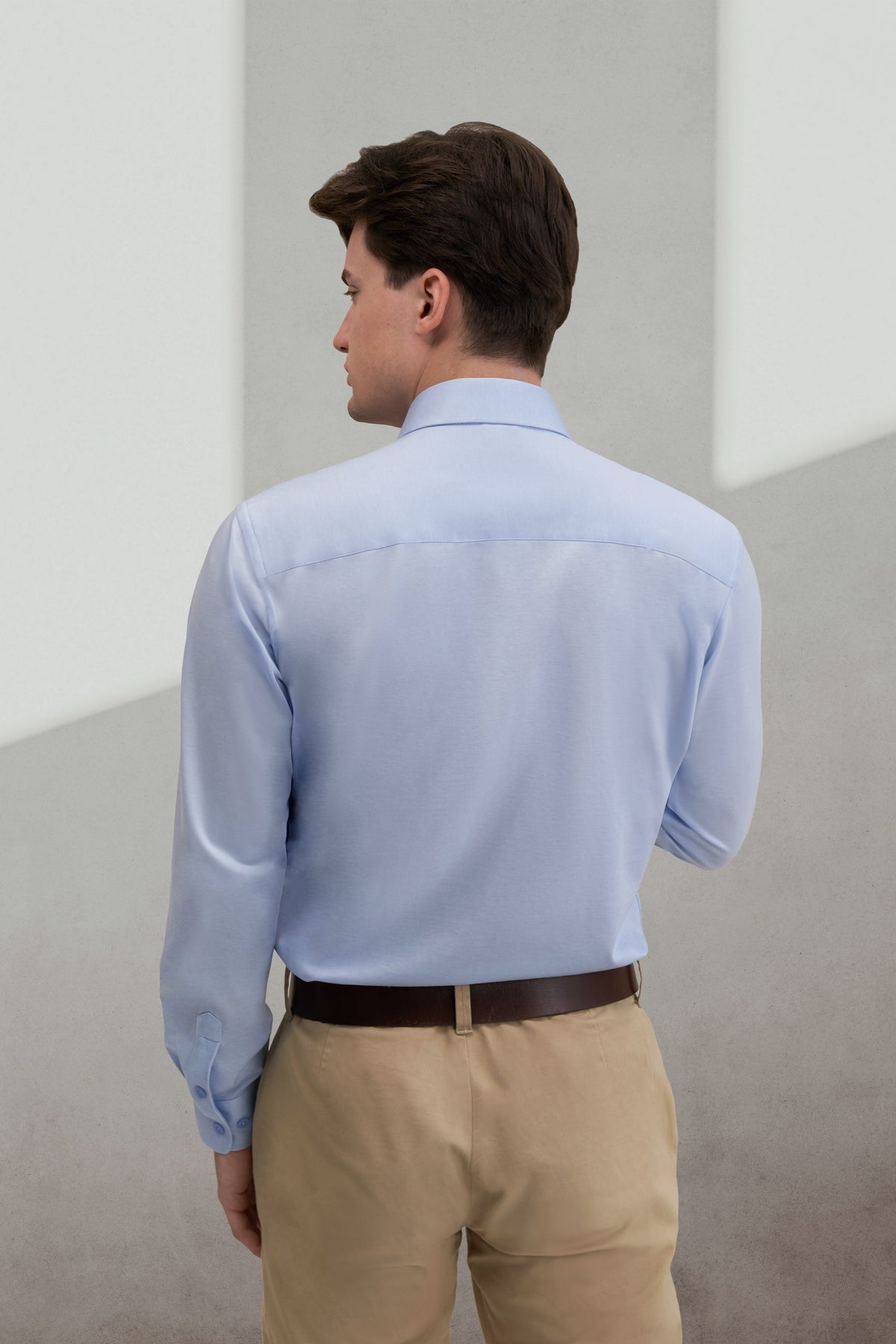 Back view of a man wearing the UNWRINKLED Soft Sky Blue light blue cotton shirt